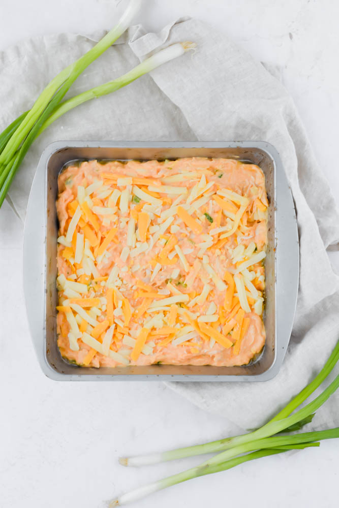 metal square pan filled with uncooked buffalo chicken dip on white background