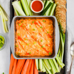 tray full of buffalo chicken dip plated with colorful vegetables and crackers
