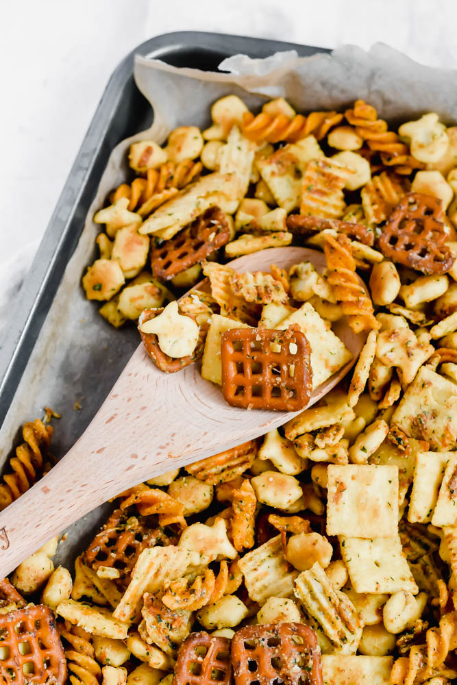 platter of ranch snack mix with wooden spoon lifting up the mix
