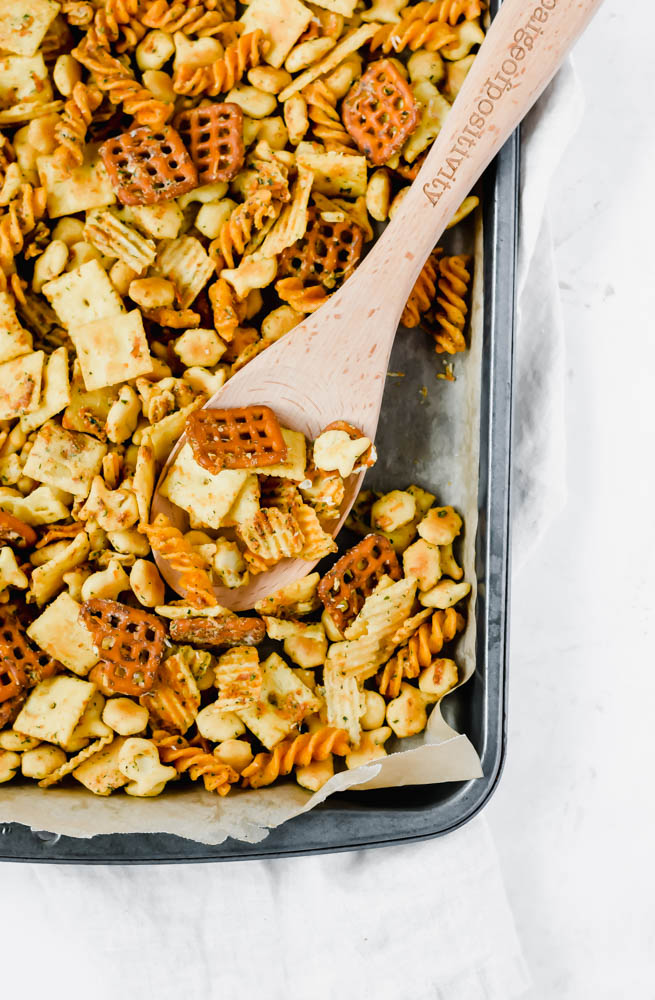 platter of ranch snack mix with wooden spoon lifting up the mix