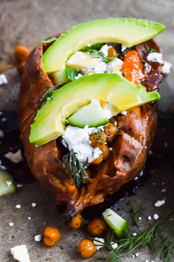 baked sweet potato loaded and garnished with fresh avocado and spicy honey