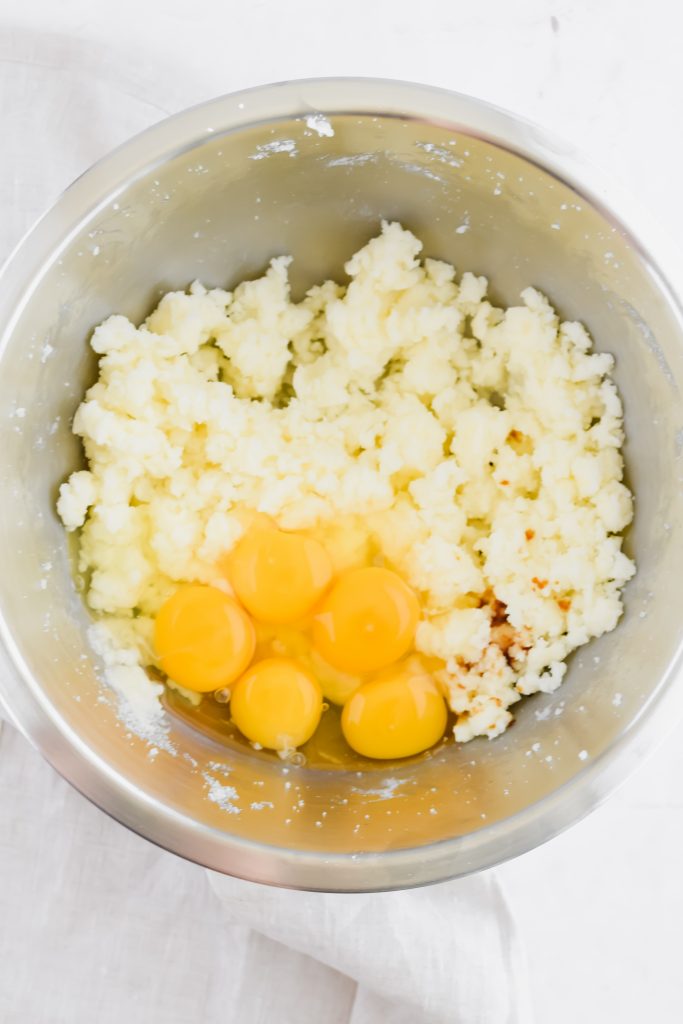 stainless steel mixing bowl with creamed butter and sugar and freshly cracked eggs