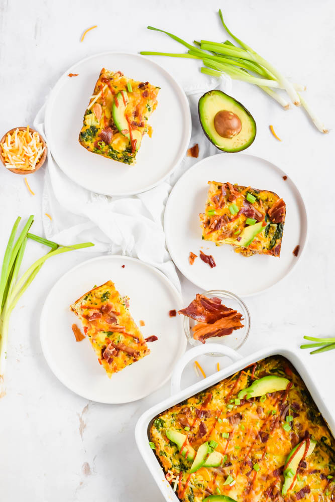 three white plates filled with bacon sweet potato and egg casserole slices and garnished with green onions and avocado