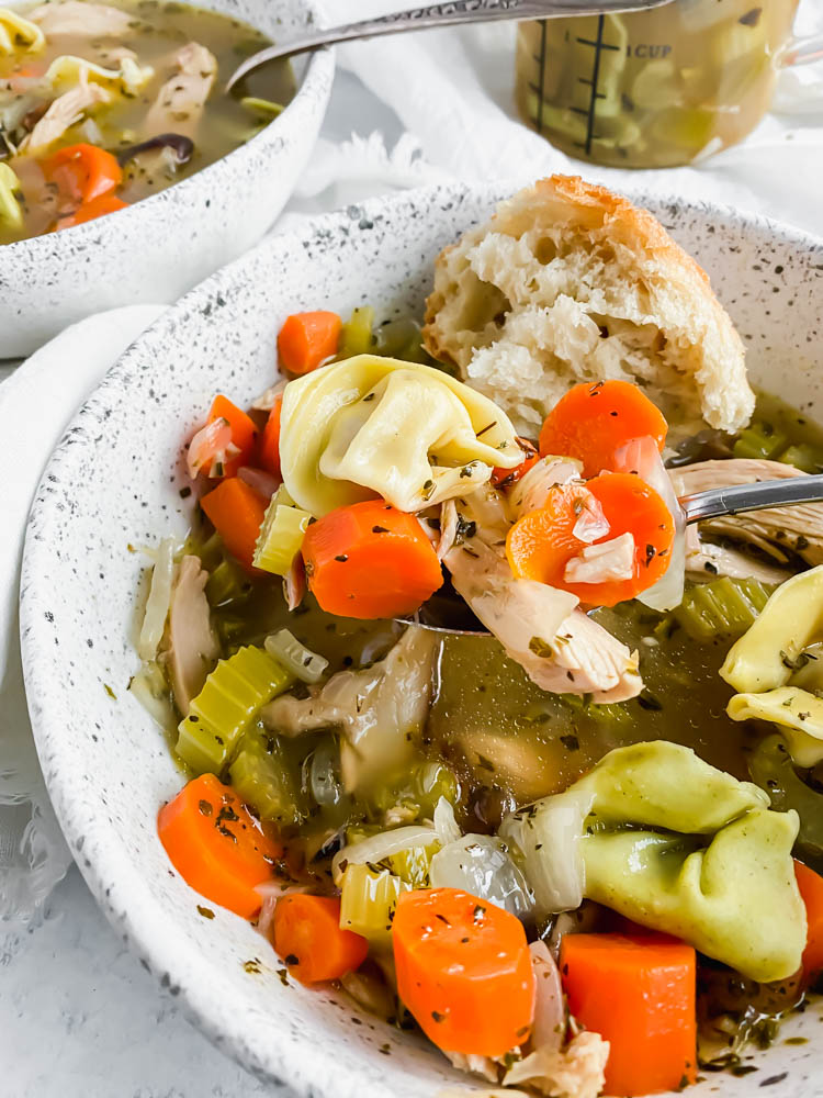 close up of cooked soup topped with all the vegetables and chicken on a large spoonful waiting to be eaten