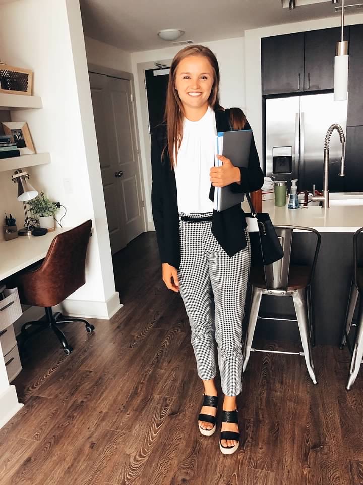 girl standing smiling in her new apartment with folder and purse in hand
