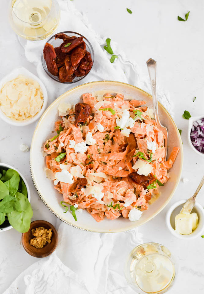 prepared sweet potato fettuccine in large serving bowl surrounded by additional recipe ingredients.