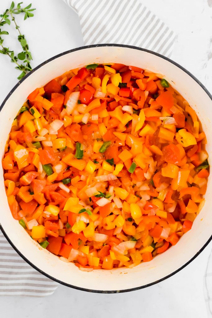 Large pot filled with fresh mixed vegetables during cooking process on striped linen backdrop