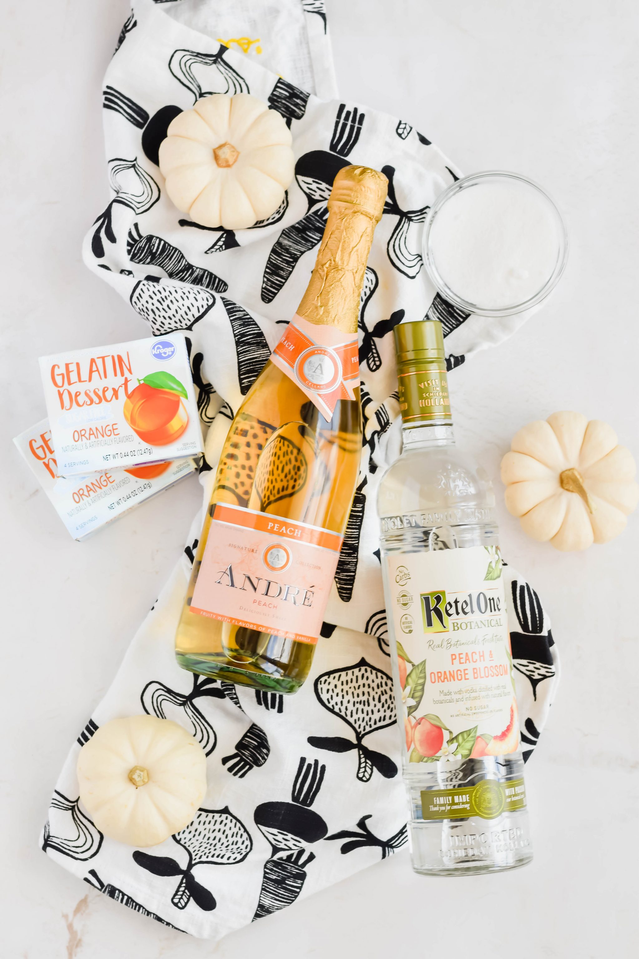 bottle of champagne, vodka, and gelatin mix boxes on patterned kitchen towel.