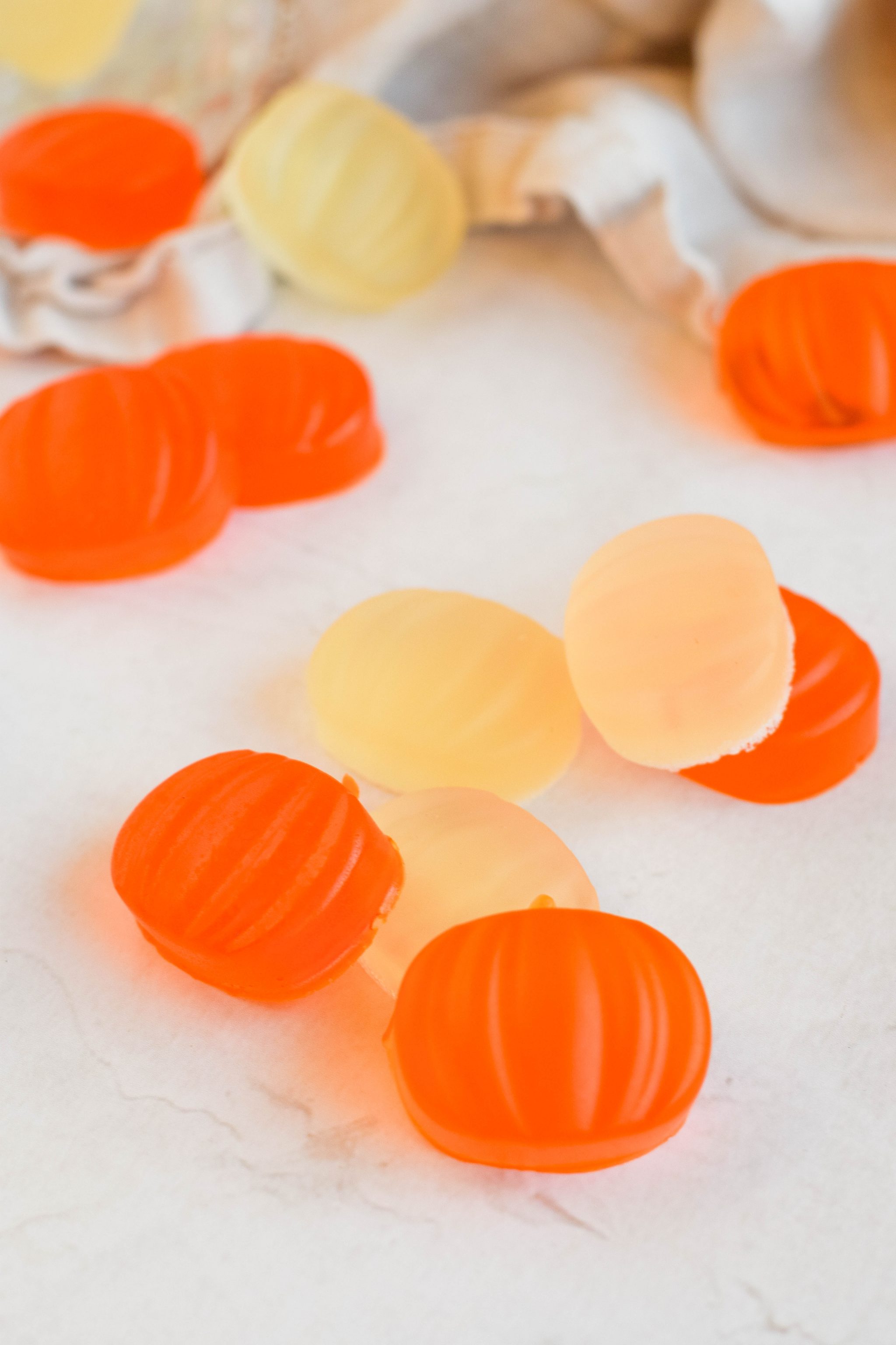 close up of pumpkin shaped halloween jello shots spread on white background.
