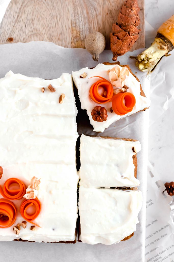 overhead shot of frosted and decorated healthier carrot cake bars on wood board