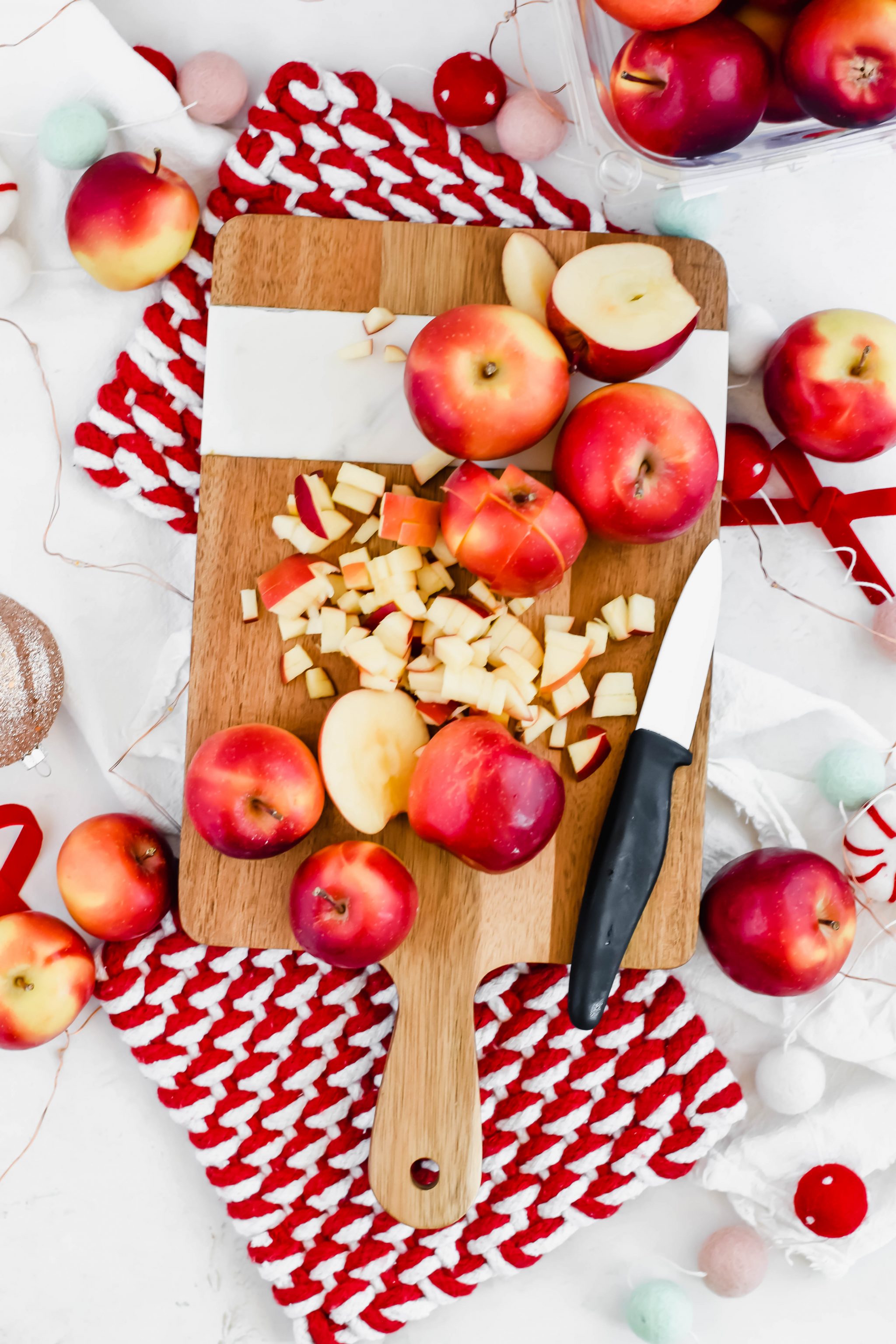 chopped rockit apples on a wooden cutting board with a ceramic knife.