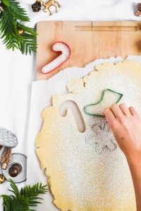 Cutting Shortbread Christmas Cookie dough with festive holiday cookie cutters.