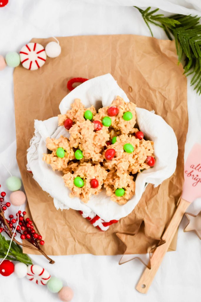 bowl of stacked no bake avalanche cookies on parchment surrounded by christmas decorations