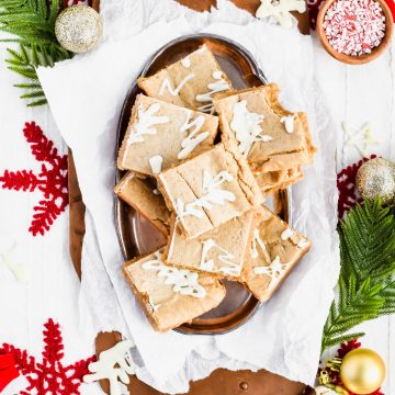 Overhead shot of Gingerbread Blondies with white chocolate on a silver serving platter with a bite taken out of one