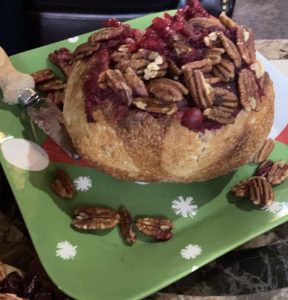 baked brie in a bread bowl topped with cranberry and pecan