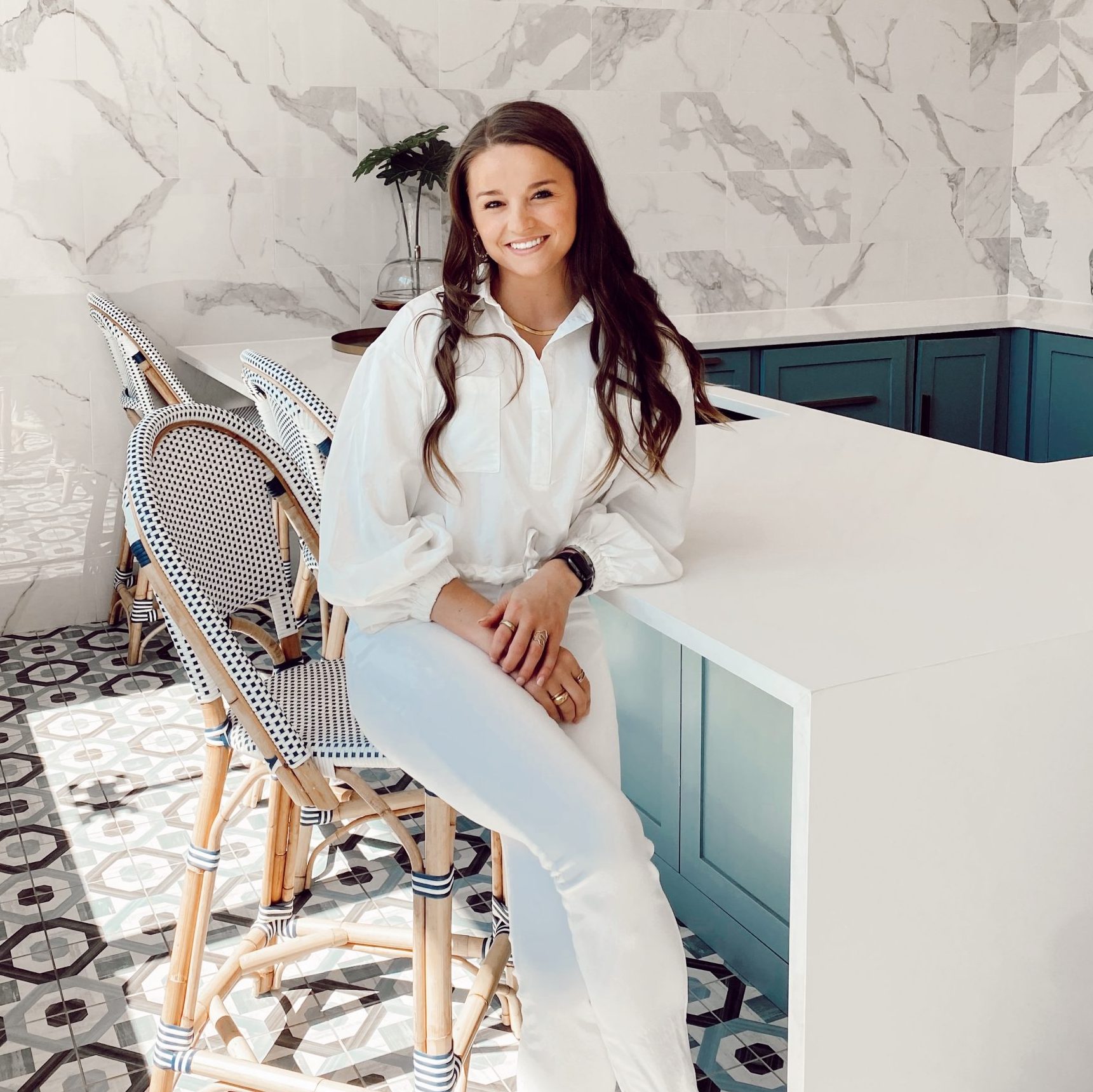 girl smiling and sitting down in a large white kitchen
