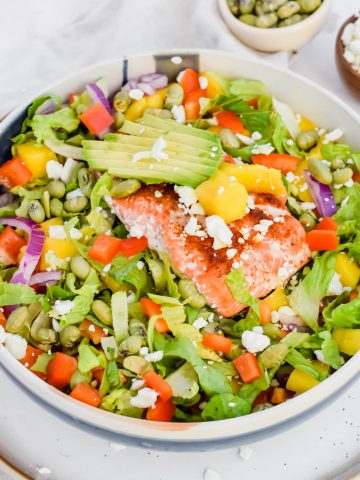 Close up of Citrus Salmon and Mango Salad in a white bowl with a blue stripe