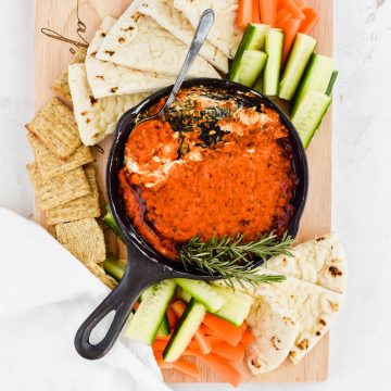 Overhead shot of copycat Romesco Sauce from Trader Joe's in a cast iron skillet served with crackers, pita bread, and fresh vegetables