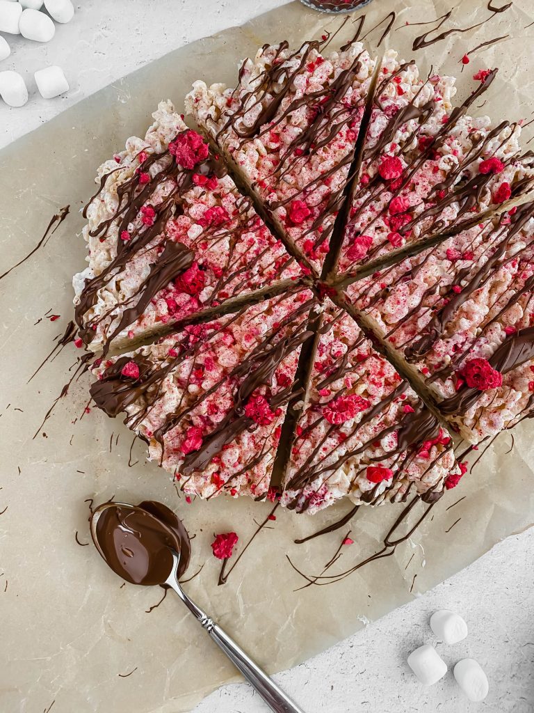 circular shaped raspberry chocolate rice krispies drizzled in chocolate and layered with fresh rasberries