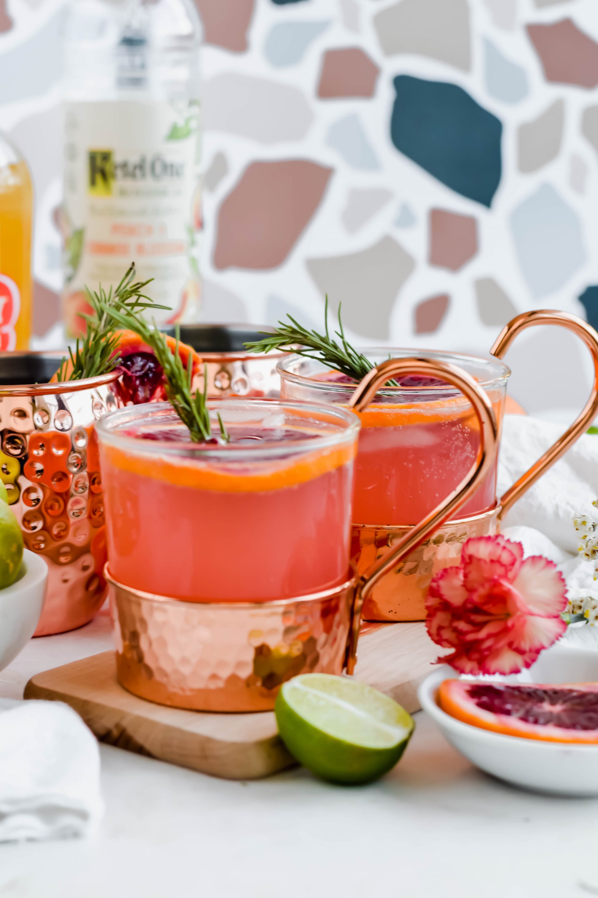 two Copper bottom mugs filled with pink moscow mules garnished with blood oranges and rosemary