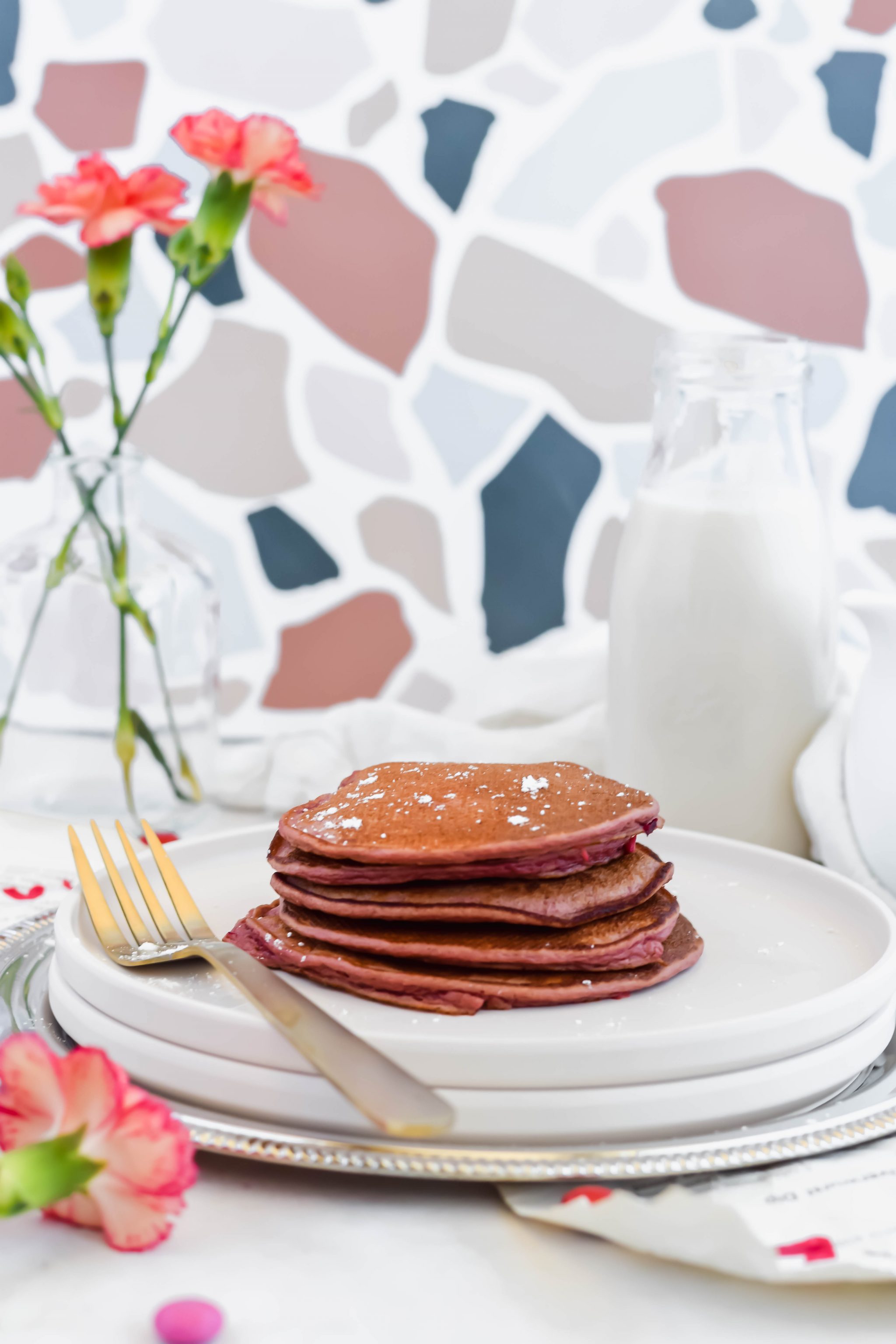 Stack of Healthy Red Velvet Protein Pancakes on a white plate with a gold fork.