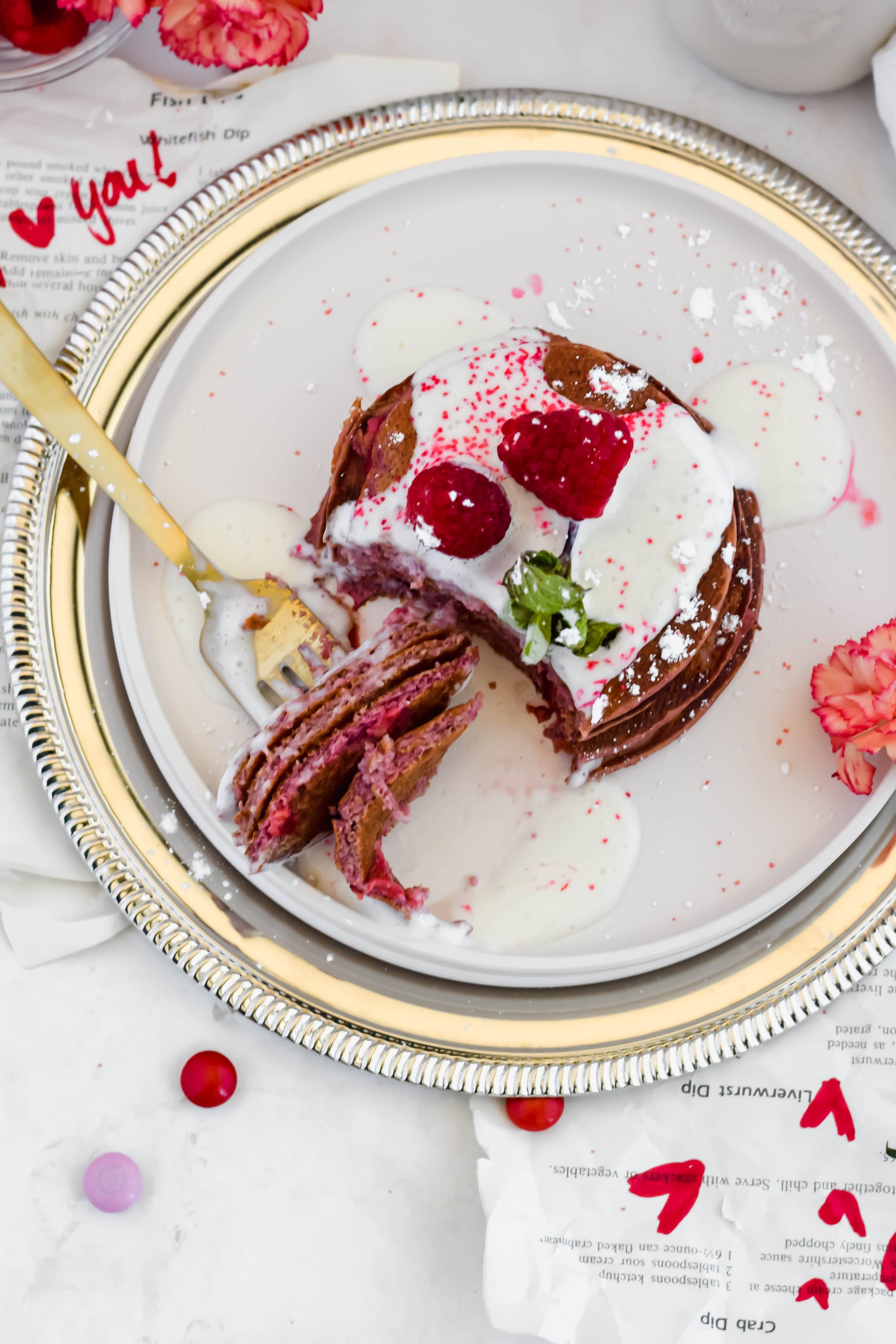 Forkful of Healthy Red Velvet Protein Pancakes covered in cream cheese frosting and fresh berries.