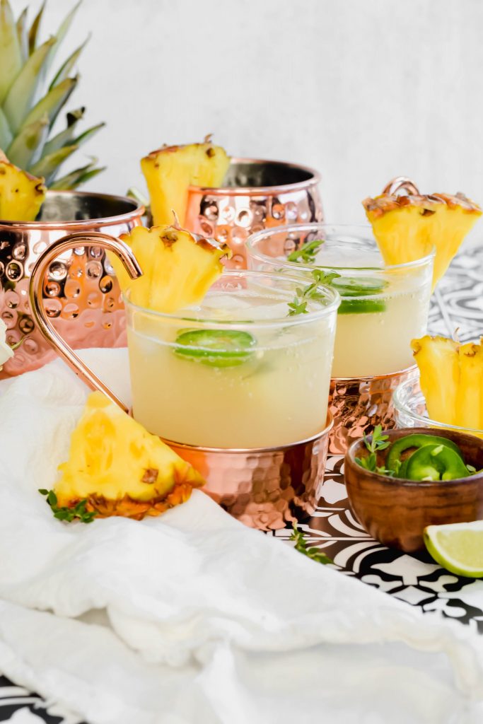 Two Pineapple Jalapeno Moscow Mules garnished with fresh pineapple and jalapeno slices