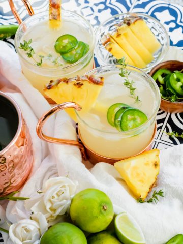 Two Pineapple Jalapeno Moscow Mules garnished with fresh pineapple and jalapeno slices