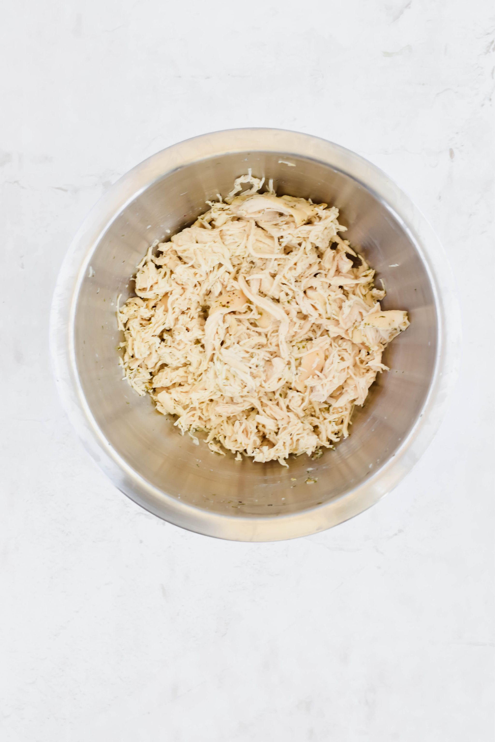 Shredded chicken in a metal mixing bowl