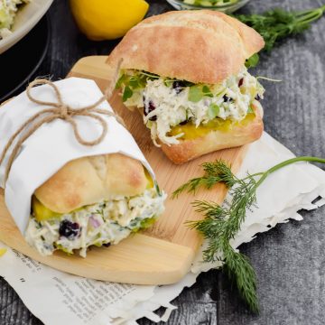 Two small sliders stuffed with Cucumber Dill Chicken Salad on a small wooden cutting board