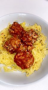 bowl of spaghetti squash topped with 4 turkey meatballs and red sauce on white background