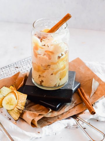 Banana Peanut Butter Overnight Oats in a tall glass with banana slices and a cinnamon stick