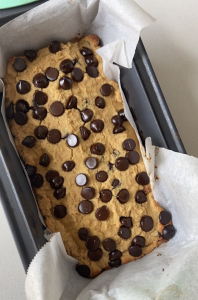 overhead shot of parchment lined bread loaf pan filled banana bread topped with chocolate chips