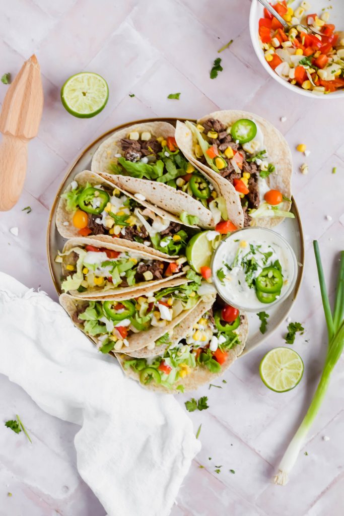 Plate of Carne Asada Street Tacos with a small bowl of coconut lime crema.
