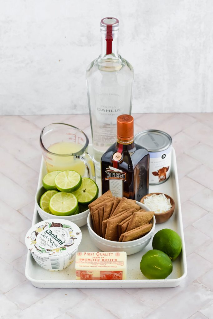 ingredients for tequila key lime pie on baking sheet on white background.