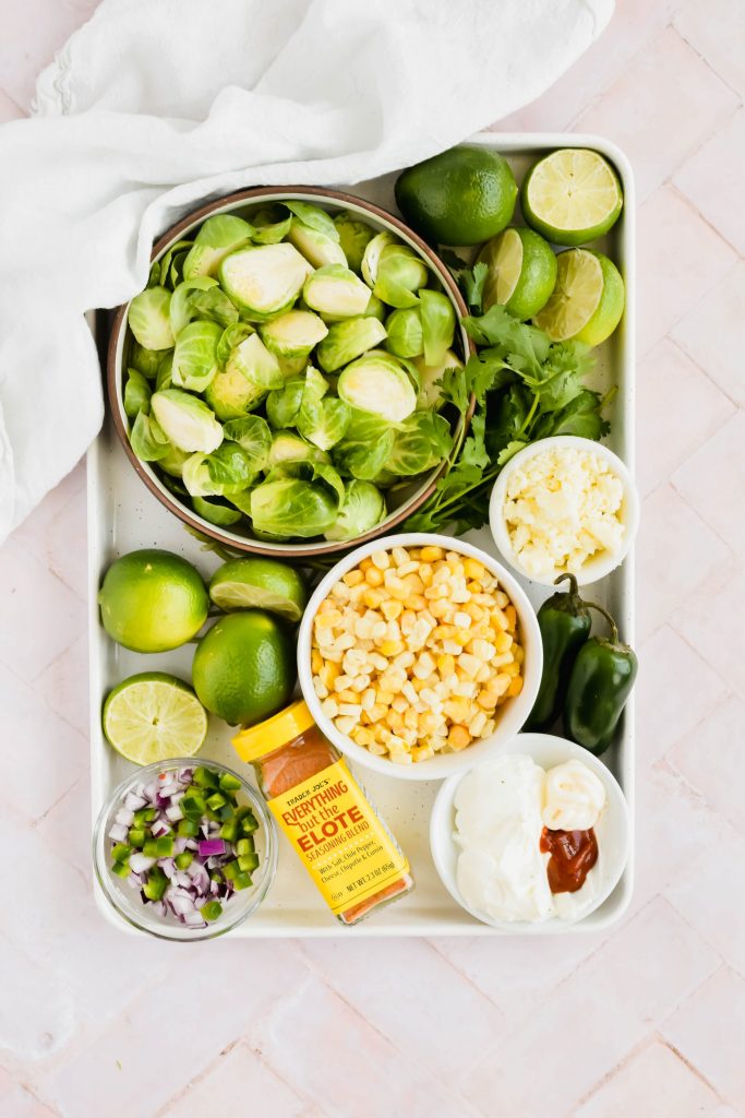 Street corn mexican brussel sprout recipe ingredients on white baking sheet on white background.