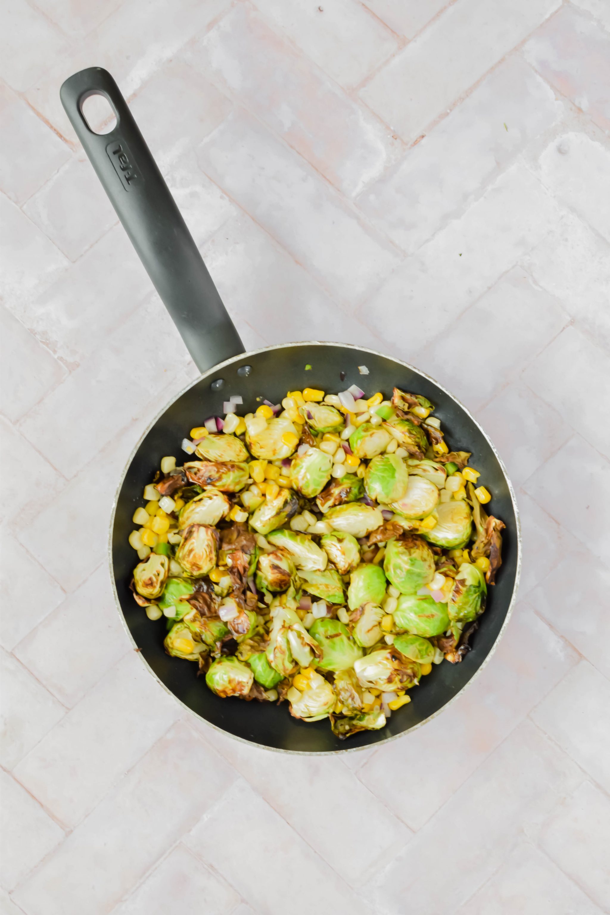Street corn mexican brussel sprouts in skillet on white background.