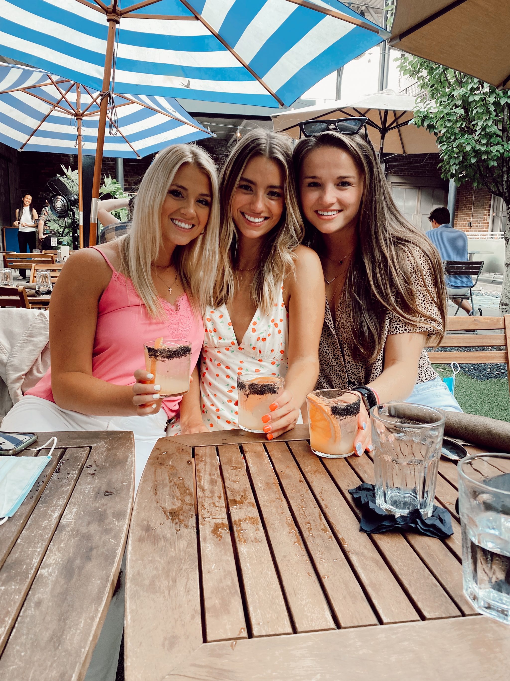 three girls sitting outside on the patio with cocktails in the summertime