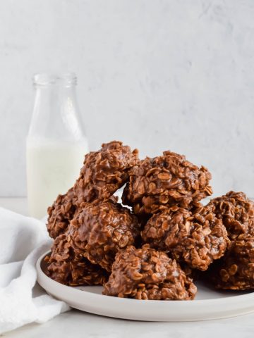 Pile of No Bake Chocolate Oatmeal Cookies without Peanut Butter on a plate with a jug of milk in the background