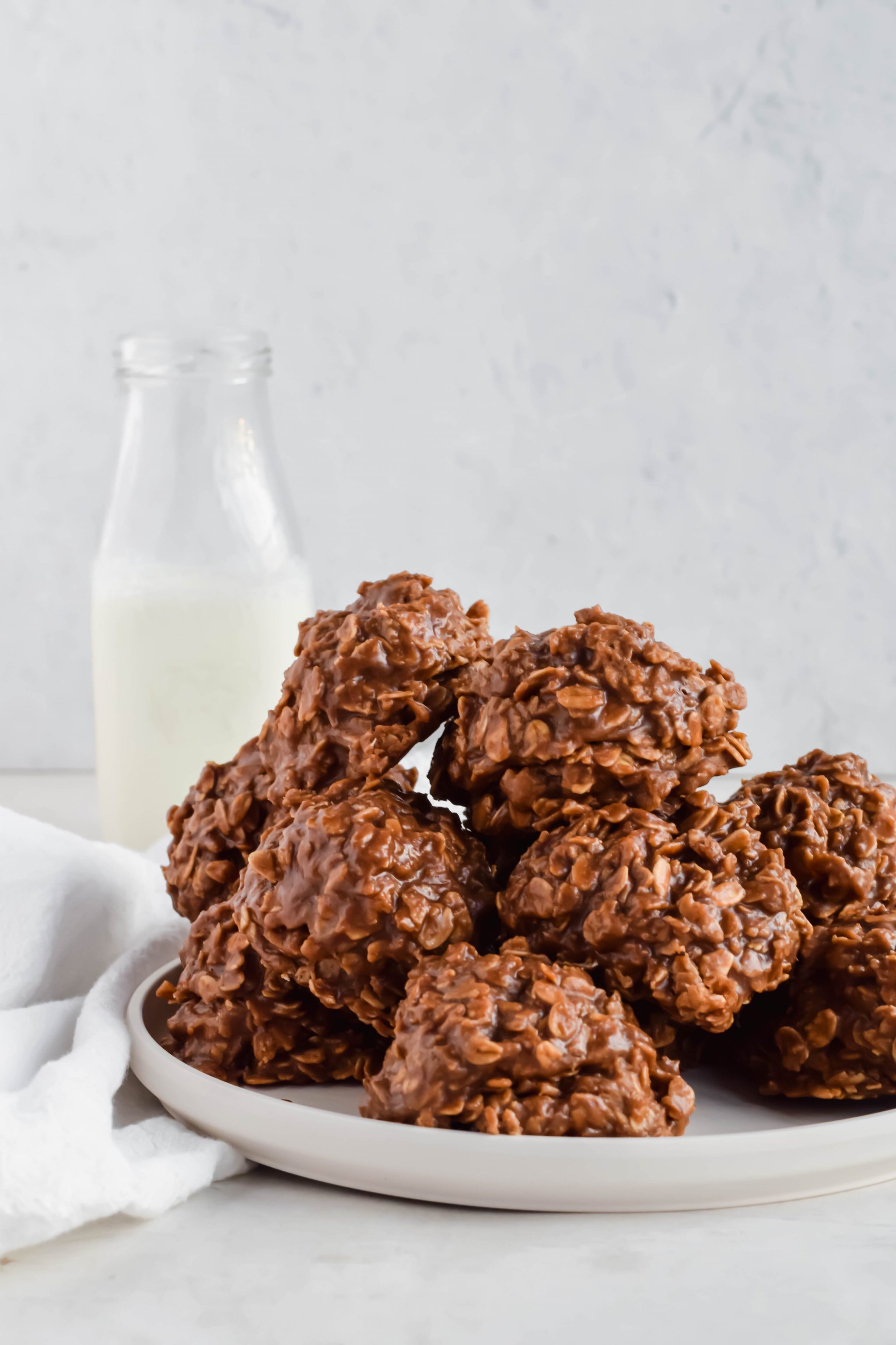 Pile of No Bake Chocolate Oatmeal Cookies without Peanut Butter on a plate with a jug of milk in the background