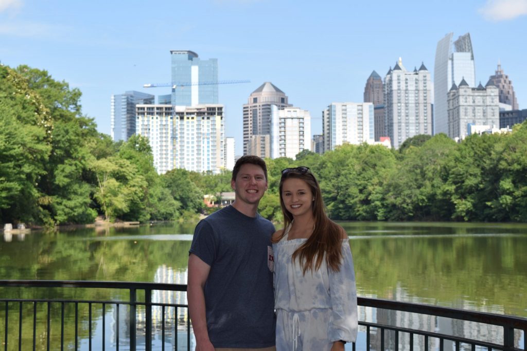 young couple in front of river front with city backdrop in the background