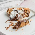 slice of chocolate coconut cream pie with whipped cream and toasted coconut topping.