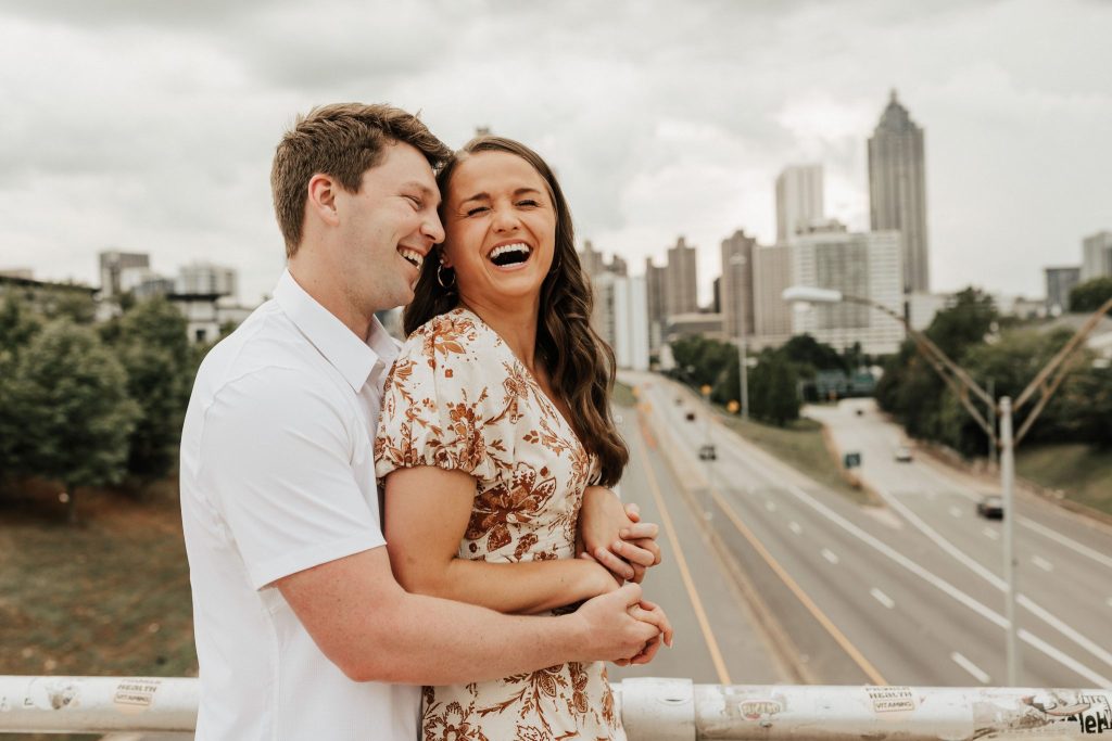 couple holding each other laughing with cityscape in the background