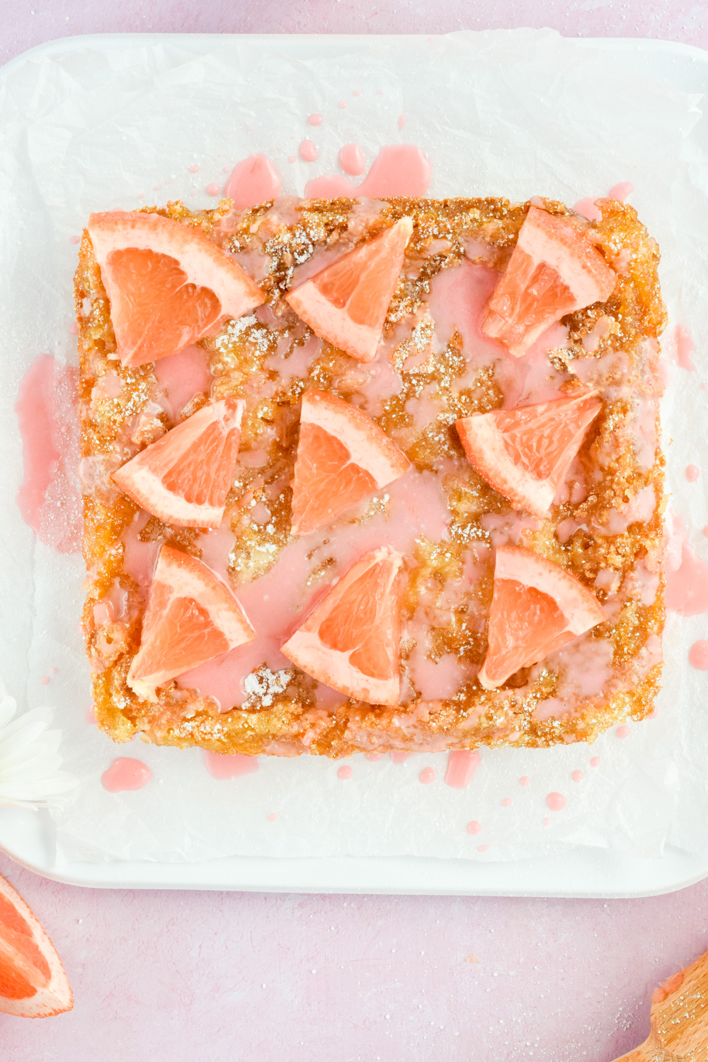 overhead shot of baked grapefruit bars on white parchment topped with grapefruit slices and grapefruit glaze.