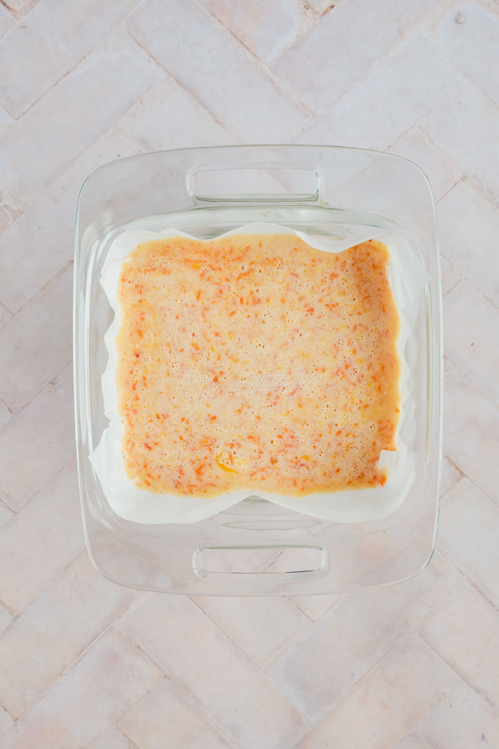 unbaked grapefruit bars in parchment lined glass baking dish.