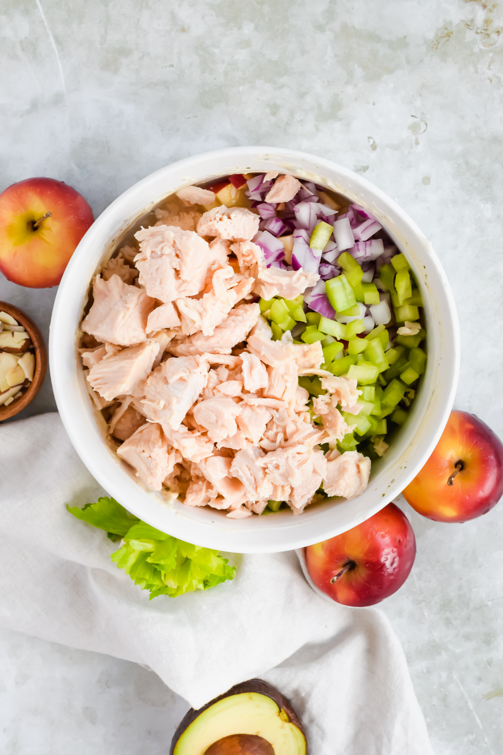 ingredients for healthy pesto chicken salad unmixed in large white bowl.