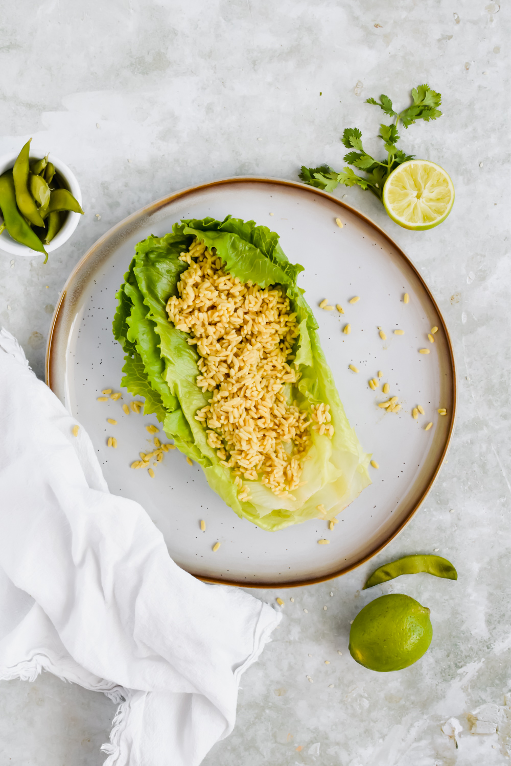 two large slices of romaine lettuce filled with right rice on white plate on gray background.