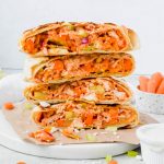 stack of four buffalo chicken crunch wrap halves on white plate.