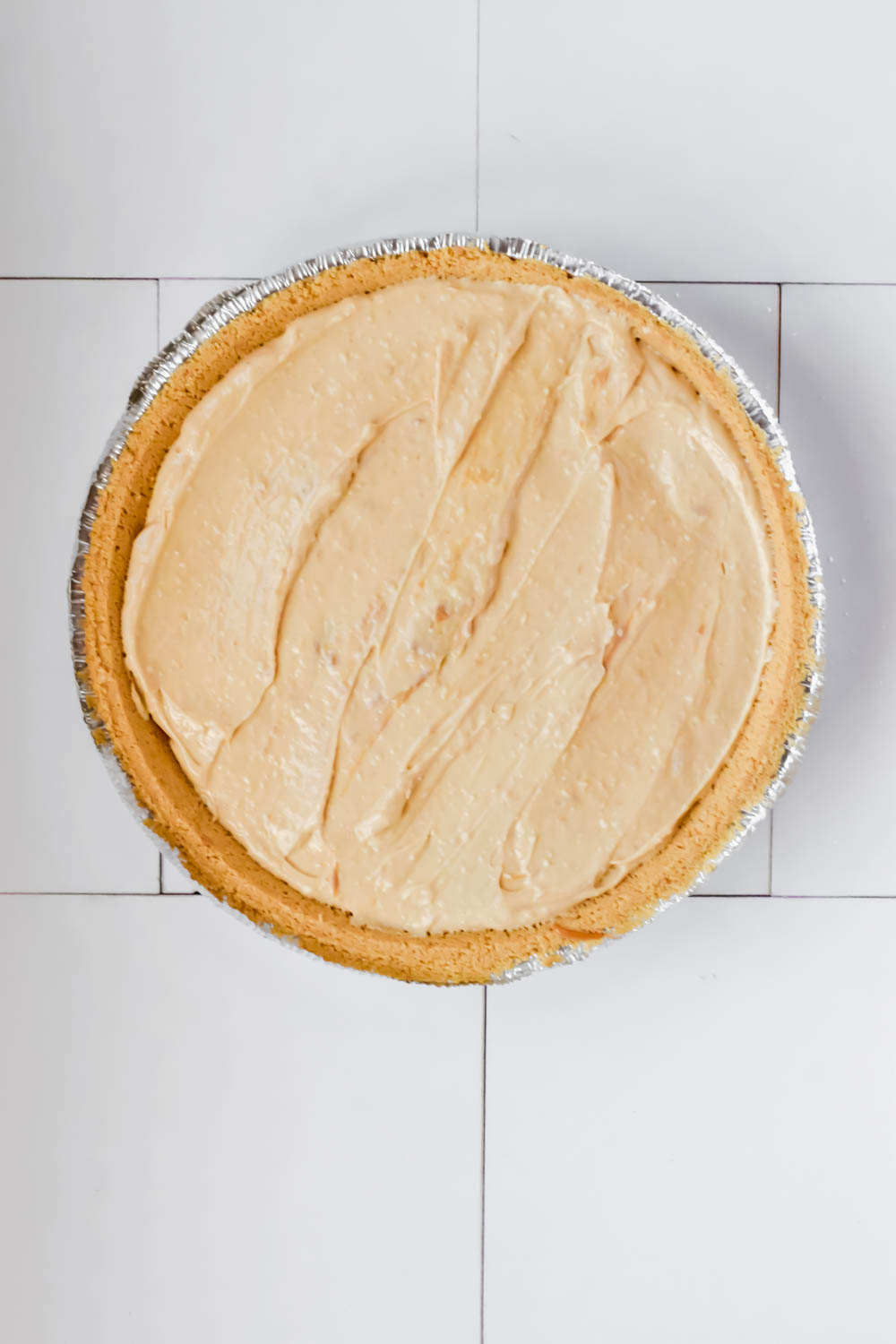 nutter butter pie in foil pie pan on white background.