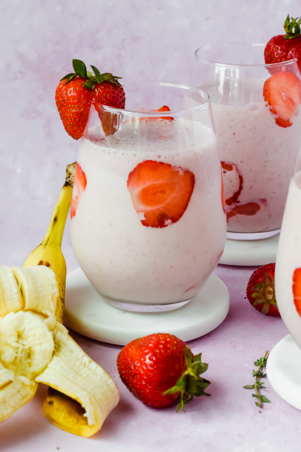 glass filled with strawberry banana protein smoothie with strawberry slices lining the glass.